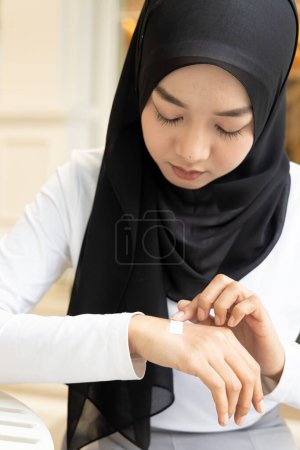 Téléchargez les photos : Femme musulmane ayant la main blessée, premiers soins traitement des blessures mineures couvrant avec un bandage propre - en image libre de droit