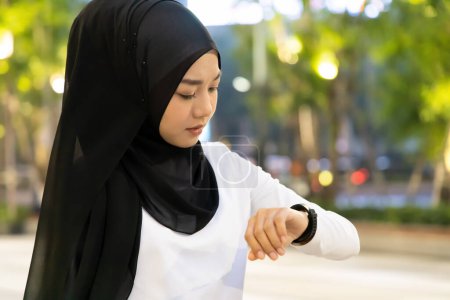 Téléchargez les photos : Malheureuse femme musulmane en attente de personnes non ponctuelles être en retard pour un rendez-vous - en image libre de droit
