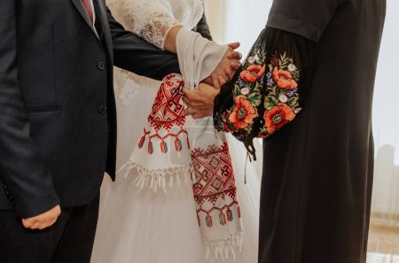 cérémonie de mariage officielle au bureau d'enregistrement. les jeunes mariés sont attachés une serviette blanche avec un ornement national sur leurs mains ensemble. ukrainain tradition rushnyk