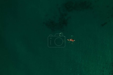Aerial top nature view above green turquoise Thracian sea Greece Ellada. Beautiful young woman bikini swimming alone middle ocean water. girl in diving mask for snorkeling. wide panoramic view marine