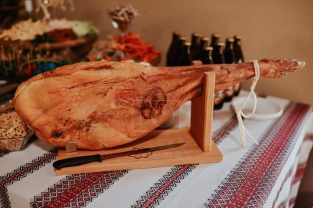 Photo for Spanish ham, Jamon Serrano, Bellota Italian.Prosciutto Crudo or Parma ham, whole leg. Italy, food. a large piece of Italian.Parma ham hanging from a hook. prosciutto leg hangs on table in display case - Royalty Free Image