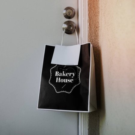Photo for Contactless delivery bakery bag mockup hanging on a door knob during the coronavirus pandemic - Royalty Free Image