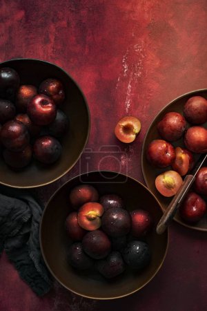 Photo for Red plums in a bowl summer food flatlay - Royalty Free Image