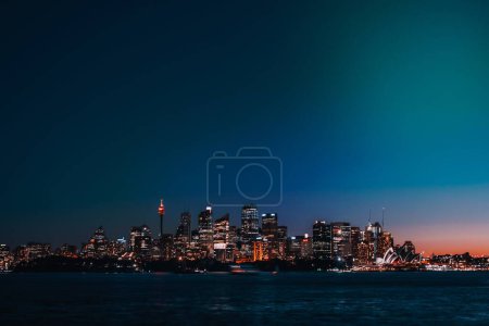 Photo for Illuminated buildings and skyscrapers in the distance, illuminated at sunset in Cremorne Reserve. - Royalty Free Image