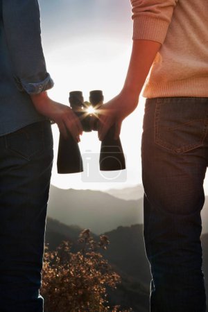 Téléchargez les photos : Jeune couple tenant des jumelles et regardant le soleil - en image libre de droit