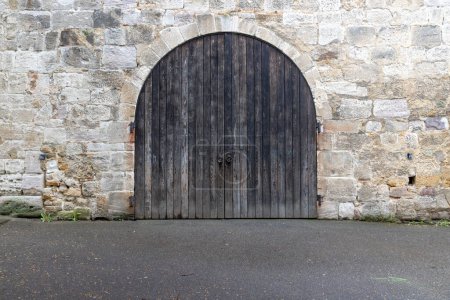 Foto de Vieja puerta de patio de madera de doble hoja en una pared de piedra de cantera - Imagen libre de derechos