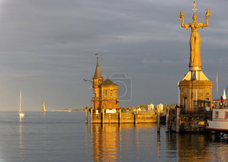 Konstanz sur le lac de Constance, entrée du port avec phare, bateaux, reflets dans le coucher de soleil orange