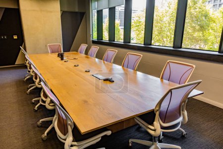 Empty executive boardroom with wooden table and fancy chairs on wheels 