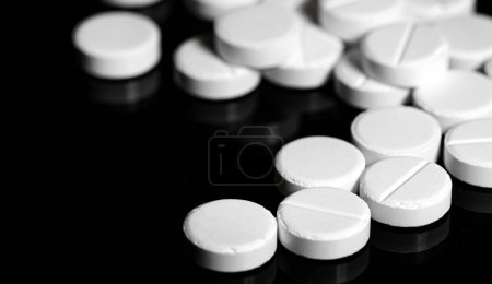 Macro Close up of white painkiller tablet on a reflective black background