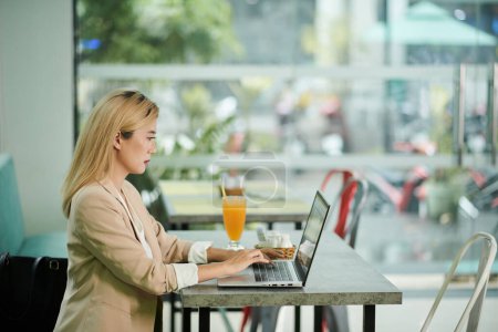 Téléchargez les photos : Serious businesswoman working on laptop in cafe - en image libre de droit