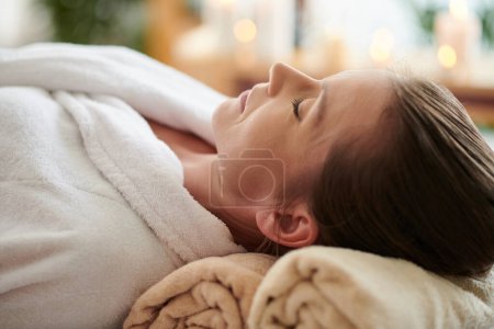 Foto de Mature woman in bathrobe relaxing in spa salon after body massage - Imagen libre de derechos