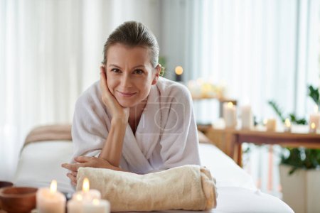 Téléchargez les photos : Smiling middle-aged woman lying in bed in spa salon after relaxing massage - en image libre de droit