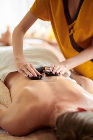 Foto de Cropped image of woman getting stone massage in spa salon - Imagen libre de derechos