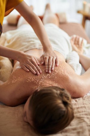 Téléchargez les photos : Woman getting deluxe spa treatment including warm seed oil and sea salt scrub - en image libre de droit
