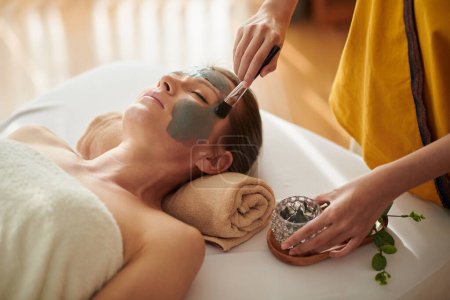 Photo for Closeup image of middle-aged woman getting sea minerals mud mask trearment in spa salon - Royalty Free Image