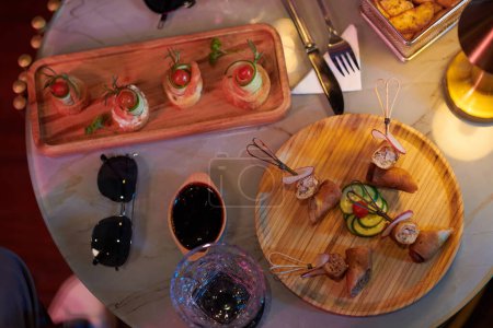Téléchargez les photos : Wooden plates with tasty snacks on round table served for group of friends, view from above - en image libre de droit