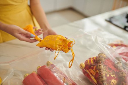 Photo for Hands of woman holding small silk yellow sack prepared for spring festival - Royalty Free Image