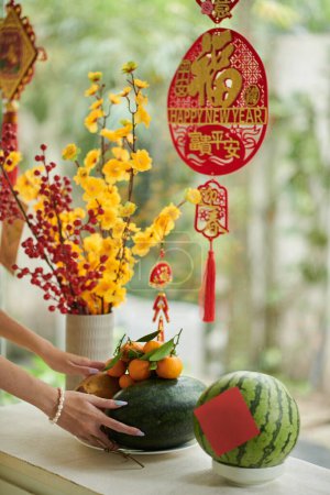 Photo for Woman putting fresh fruits on window sill when getting ready for Tet celebration - Royalty Free Image