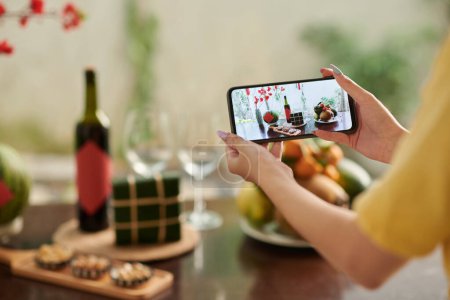 Téléchargez les photos : Hands of woman photographing dinner table served for Tet celebration - en image libre de droit