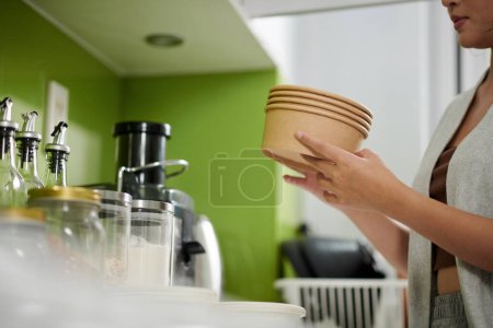 Photo for Woman taking out disposable bowls to serve breakfast oatmeal or muesli - Royalty Free Image