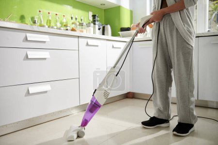 Photo for Woman cleaning kitchen floor with steam mop after cooking - Royalty Free Image