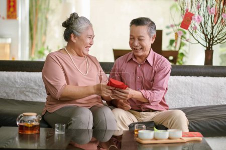Téléchargez les photos : Smiling senior couple exchaning Chinese New Year gifts - en image libre de droit