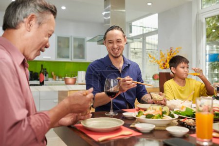 Photo for Happy mature man enjoyig family dinner with his father and preteen son - Royalty Free Image