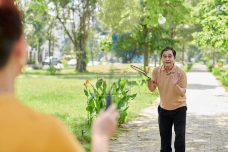 Photo for Senior man playing badminton with his wife in city park - Royalty Free Image