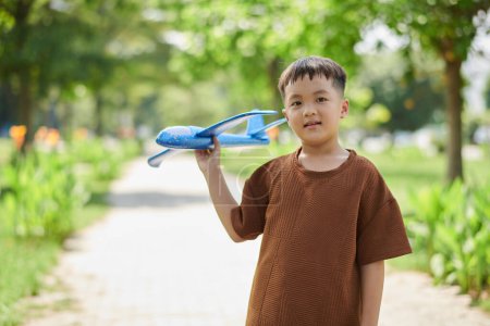 Photo for Portrait of preteen boy playing with toy plane in city park - Royalty Free Image