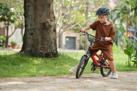 Téléchargez les photos : Little boy wearing protective helmet when riding bicycle in park - en image libre de droit