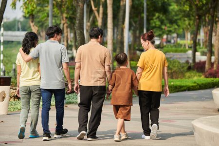 Photo for Little boy, his parents and grandparents walking in park together. view from back - Royalty Free Image