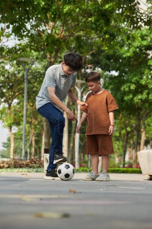Photo for Father explaining son how to kick soccer ball - Royalty Free Image