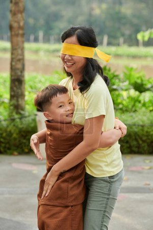 Photo for Little boy hugging his blindfolded mother when they are playing hide and seek - Royalty Free Image