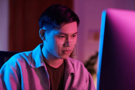 Téléchargez les photos : Serious teenage boy staying awake all night long playing on computer - en image libre de droit