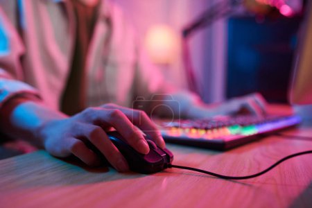 Foto de Hand of teenage boy using keyboard and mouse when playing videogame at home - Imagen libre de derechos