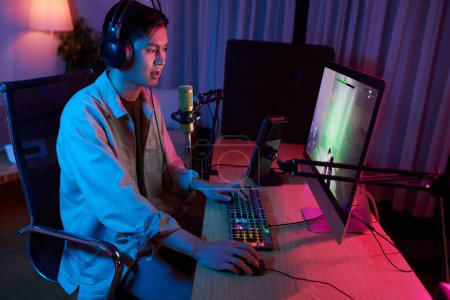 Téléchargez les photos : Letsplayer speaking in microphone when recording himself playing videogame - en image libre de droit
