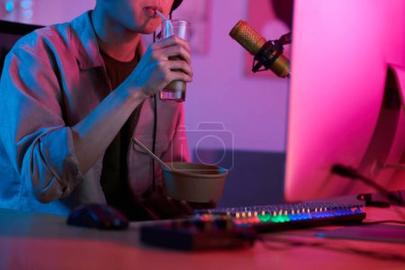 Téléchargez les photos : Gamer enjoying refreshing drink when playing videogame on computer - en image libre de droit