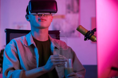 Foto de Teenage boy in virtual reality headset sipping soft drink - Imagen libre de derechos