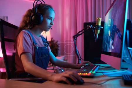 Foto de Concentrated teenage girl playing new popular videogame - Imagen libre de derechos