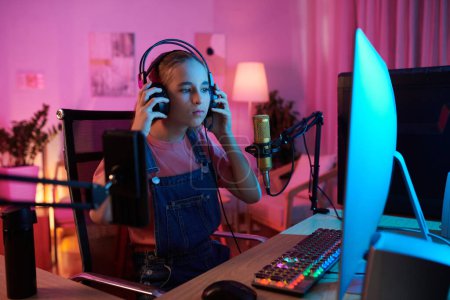 Foto de Teenage girl putting on headset for playing online videogame with friends - Imagen libre de derechos