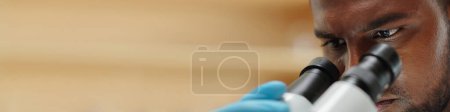 Photo for Closeup image of serious researcher looking though microscope - Royalty Free Image