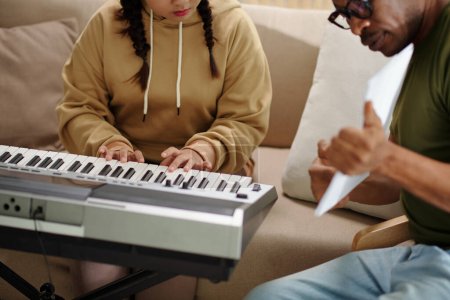 Photo for Teenage girl leaning playing synthesizer with private teacher - Royalty Free Image
