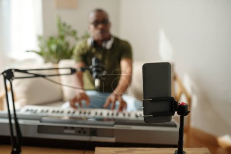 Foto de Artist set smartphone to film himself playing synthesizer at home - Imagen libre de derechos