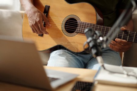 Téléchargez les photos : Closeup image of artist playing guitar at home and recording sound with microphone - en image libre de droit