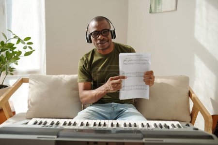 Téléchargez les photos : Happy proud man showing music notes for song he wrote - en image libre de droit