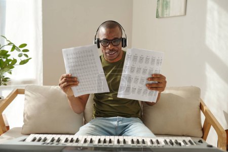 Téléchargez les photos : Happy music teacher showing papers with music notes exercises - en image libre de droit