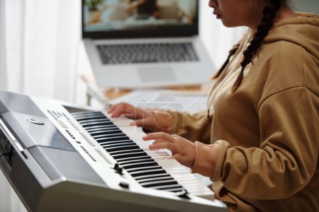 Foto de Closeup image of girl playing new song on synthesizer when having online class - Imagen libre de derechos