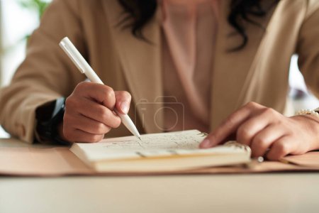Téléchargez les photos : Femme écrivant des idées et dessinant des croquis dans le planificateur - en image libre de droit