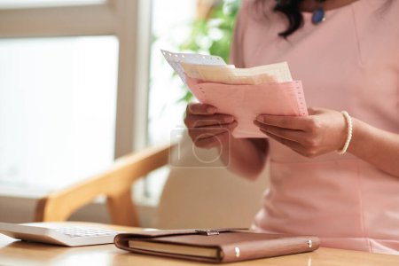 Téléchargez les photos : Mains de femme vérifiant les chèques de paie et les factures lors de la gestion des finances personnelles - en image libre de droit