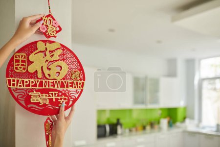 Foto de Hands of woman hanging round pedant on wall to decorate house for Lunar festival - Imagen libre de derechos